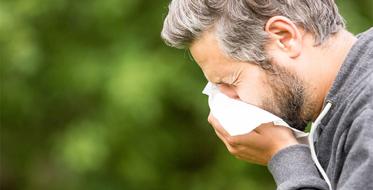 Man sneezing because of summer allergies