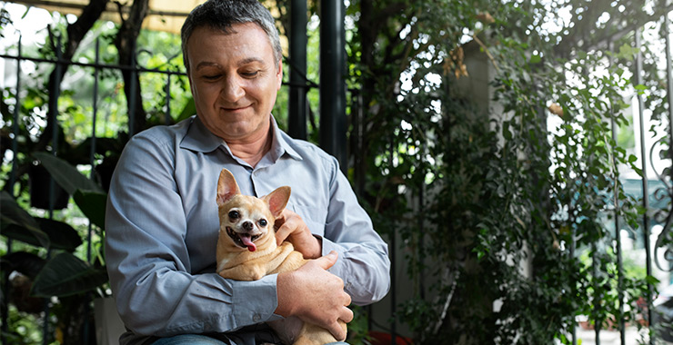 Man in garden happy holding small dog