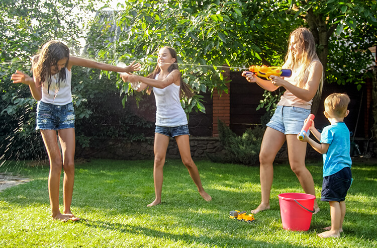 happy mom with kids playing with water in the shade on a hot sunny day avoiding heat rash