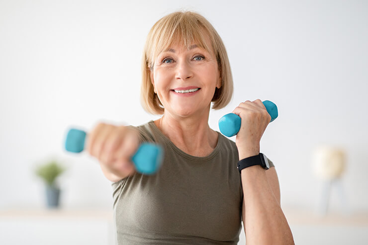 senior woman doing exercises with dumbbells indoors to build bone health after 40