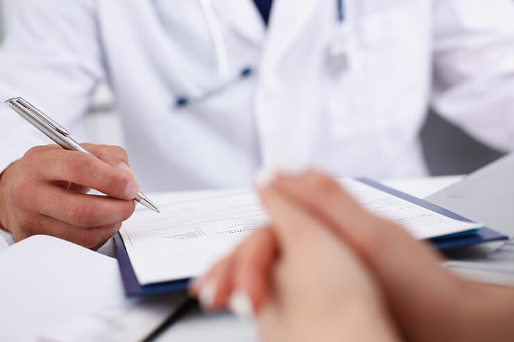 Male doctor writing with silver pen patient symptoms and concerns at urgent care for STD testing
